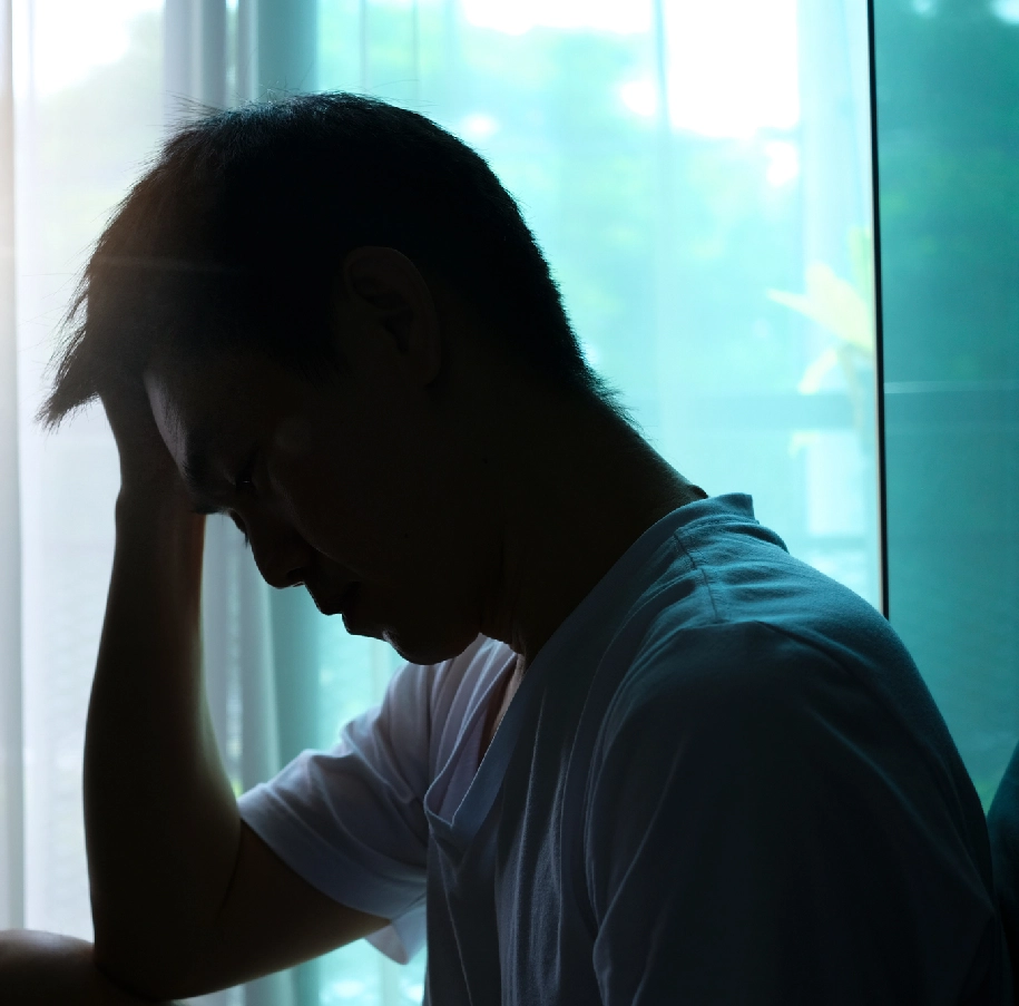 Silhouette of a man with his head down.