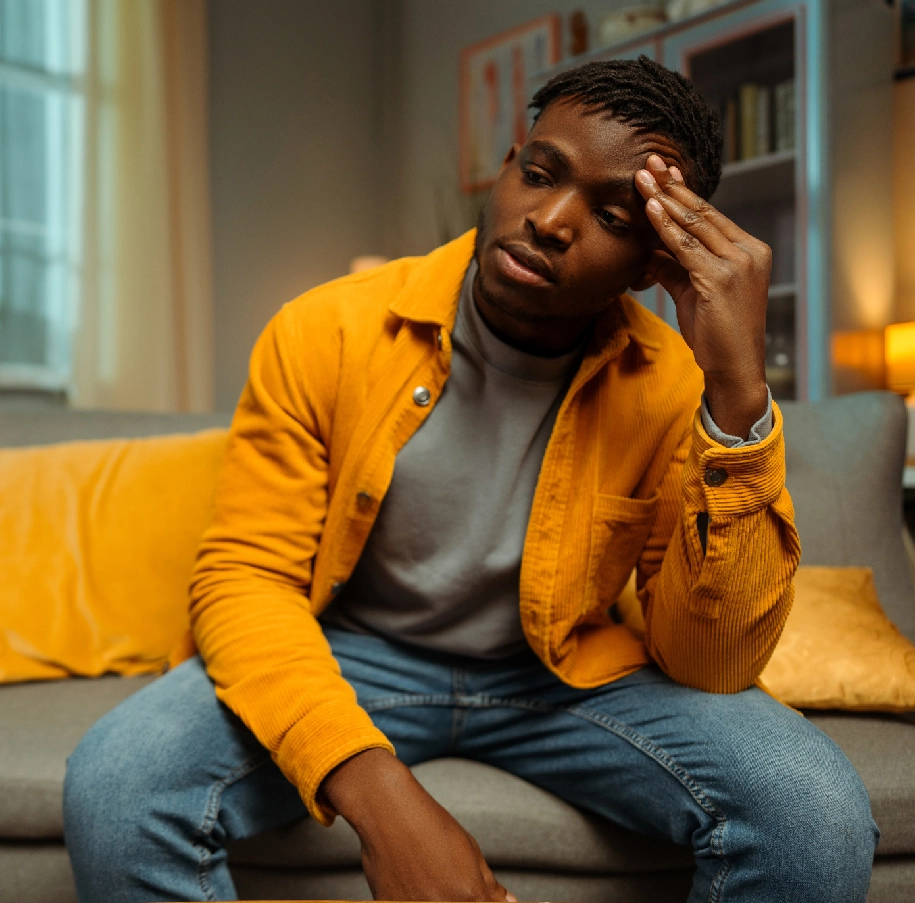 Man in yellow jacket sits on couch.