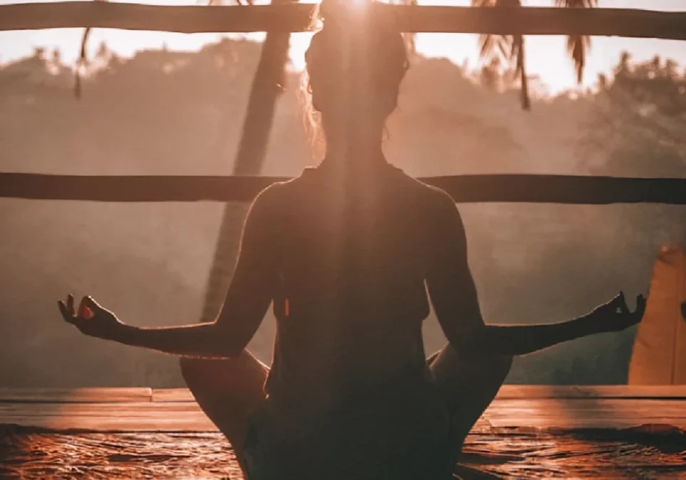 Silhouette of a woman meditating at sunset.