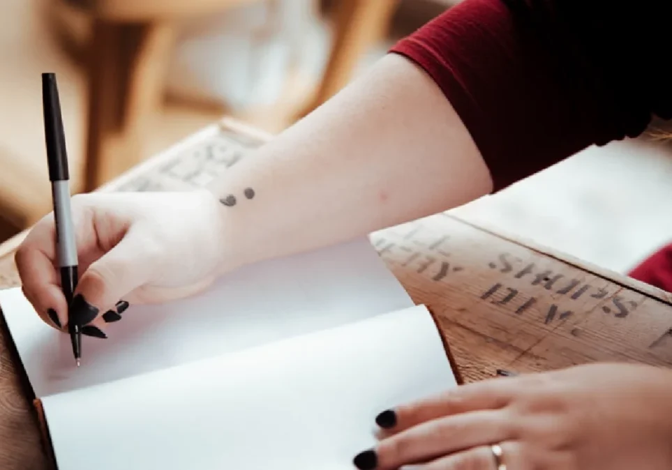 Woman writing in notebook with pen.